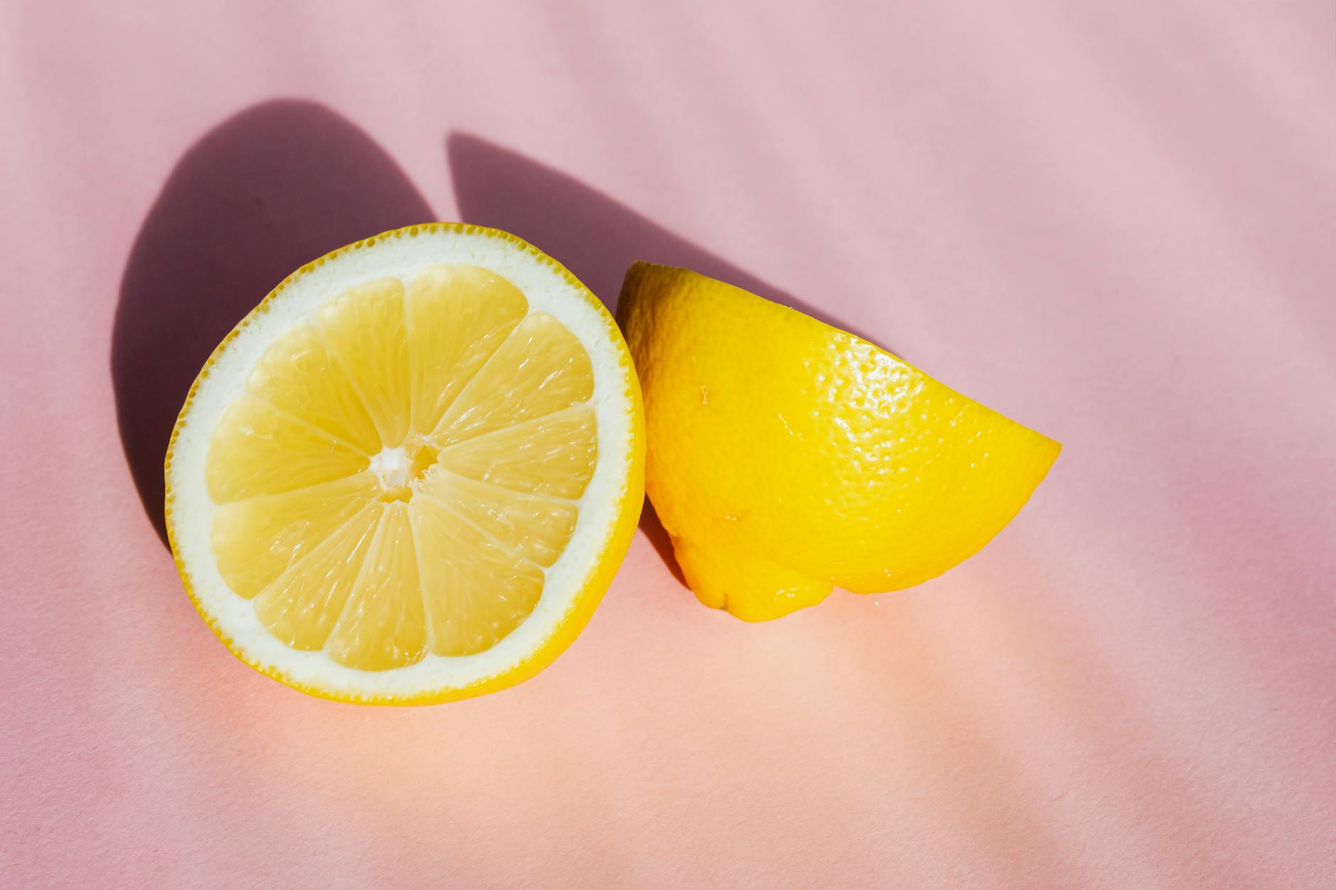 Fresh halves of lemon on pink background in sunlight, symbolizing refreshed intimacy