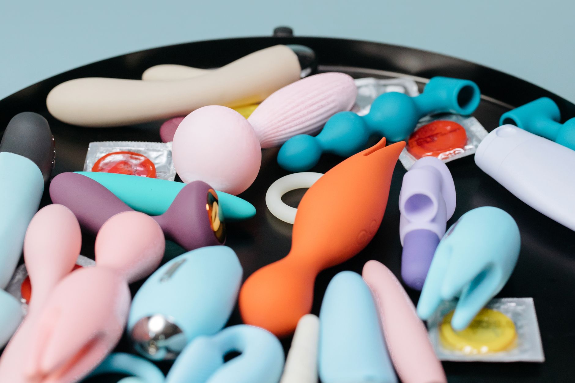 A vibrant collection of colorful sex toys on a black tray, featuring diverse shapes and colors.