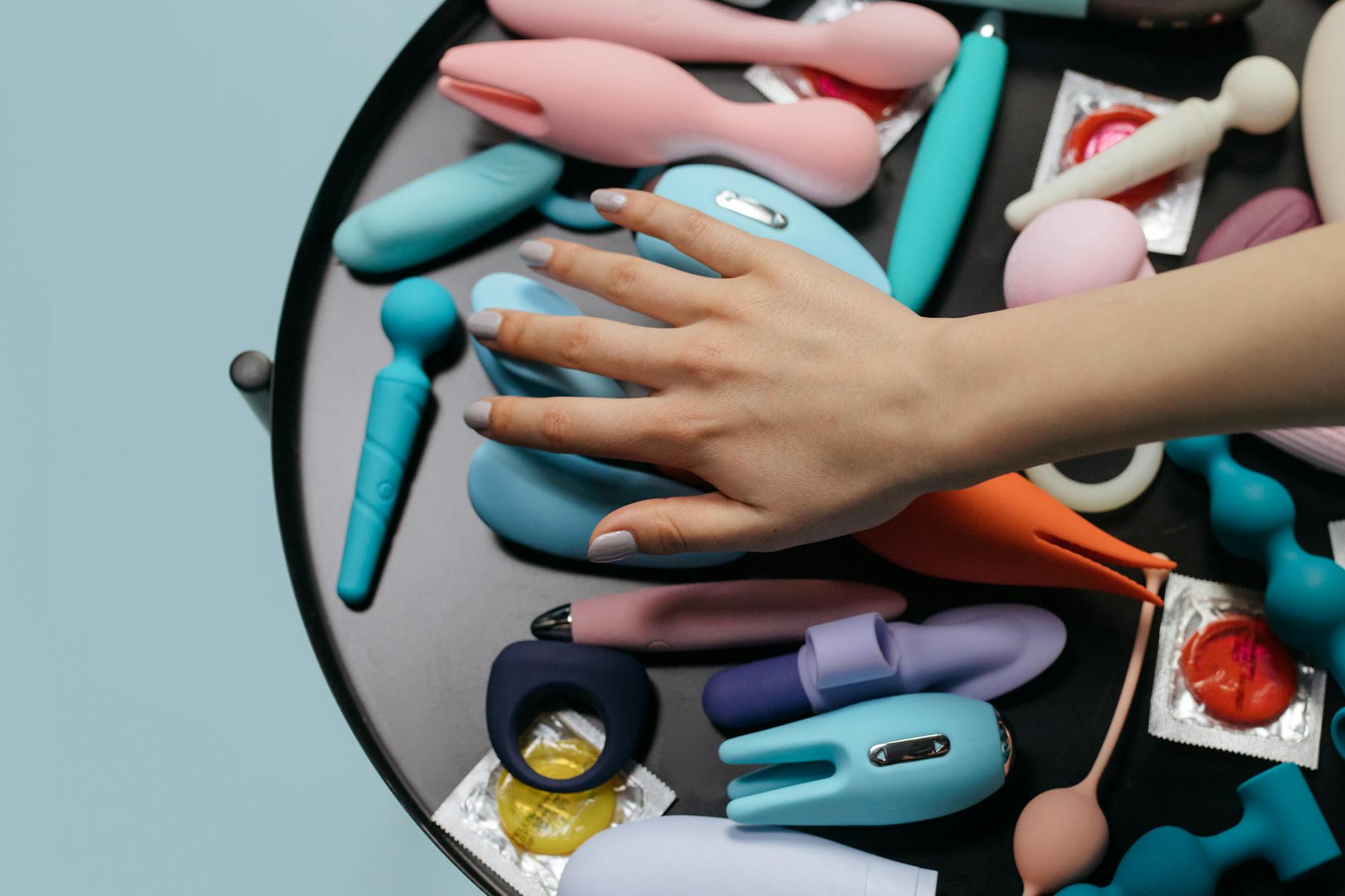 Woman holding blue and pink silicone vibrators with a contemplative expression