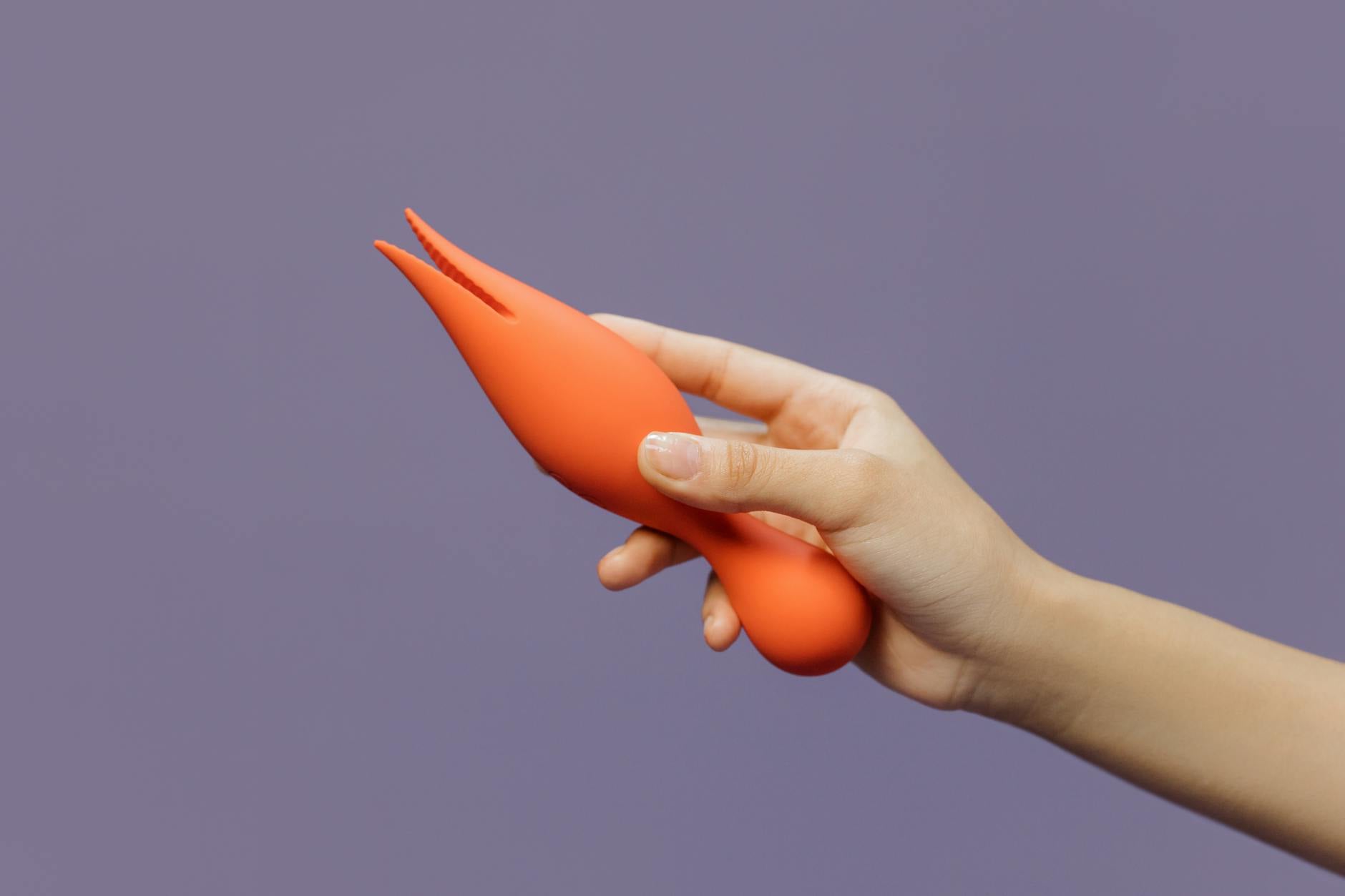 Hand holding a lemon-colored vibrator against a purple background, symbolizing self-pleasure and personal intimacy
