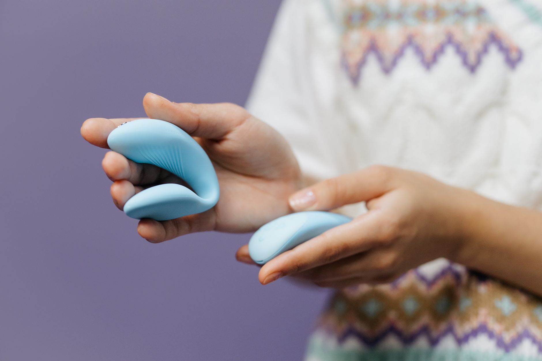 Close-up of hands holding a sleek lemon vibrator against a purple background, symbolizing modern intimacy during hormonal transitions.