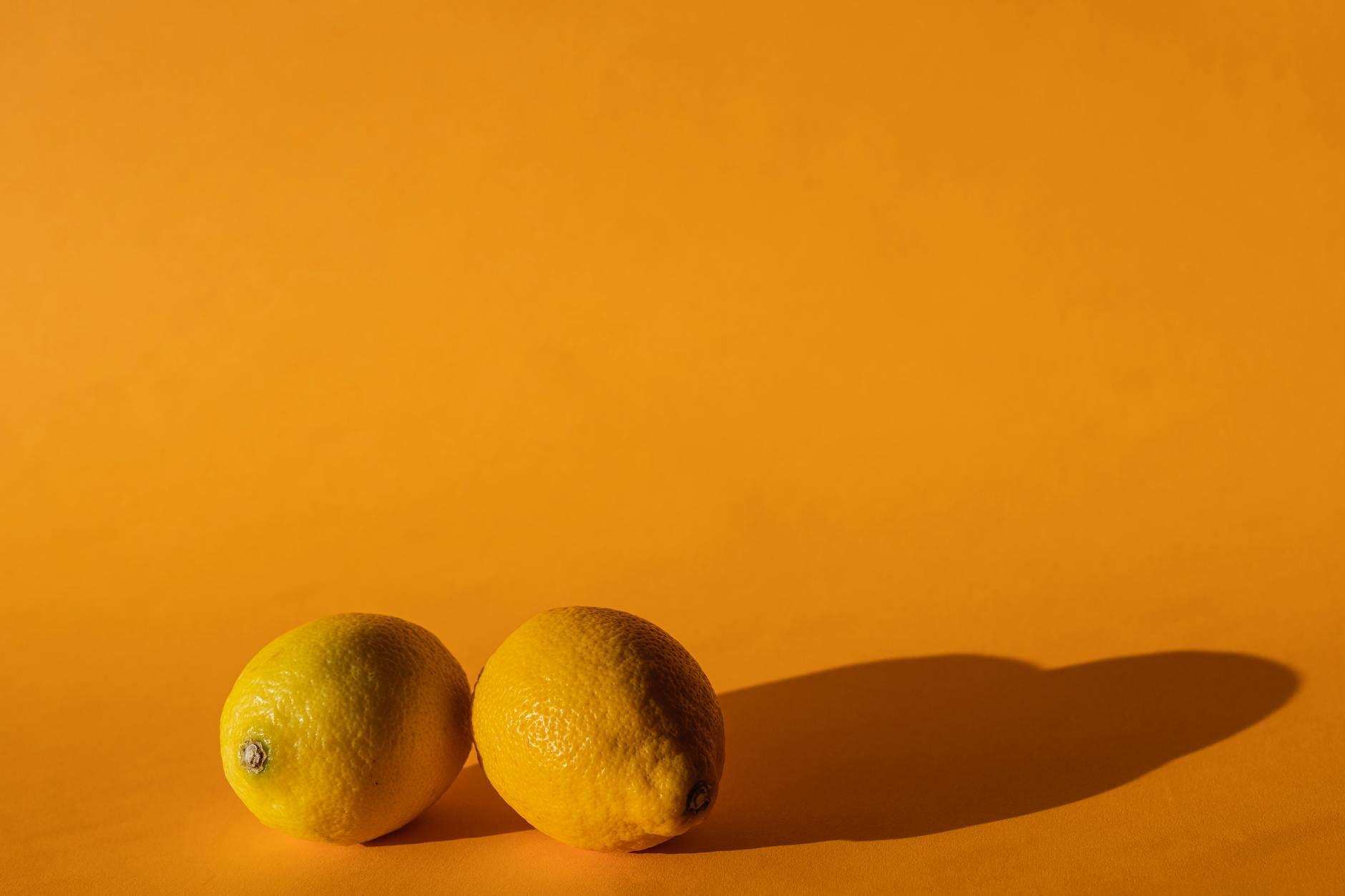 A hand holding a sleek blue lemon vibrator against a purple background